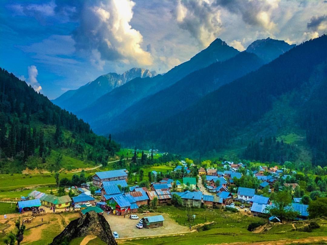 Aru Valley with green meadows, wooden huts, and snow-capped mountains